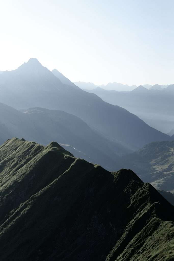Ausblick von der Höferspitze über einen schmalen Grat bei Morgenlicht in den Alpen.